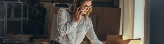 A woman talking on the phone looking down at an open box